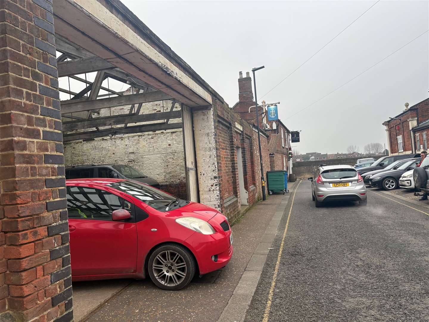 A security guard sits in a red car monitoring passersby of the painting